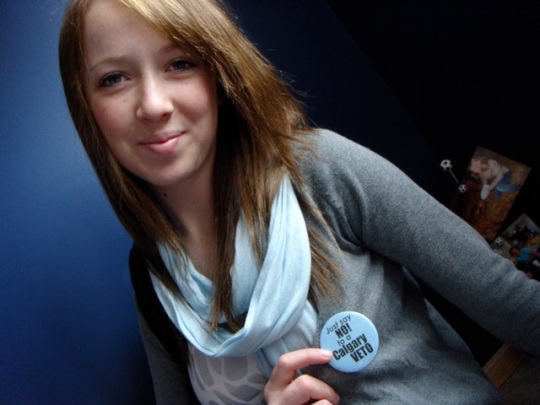 Emily shows the "blob blue" button for the No Calgary Veto campaign.